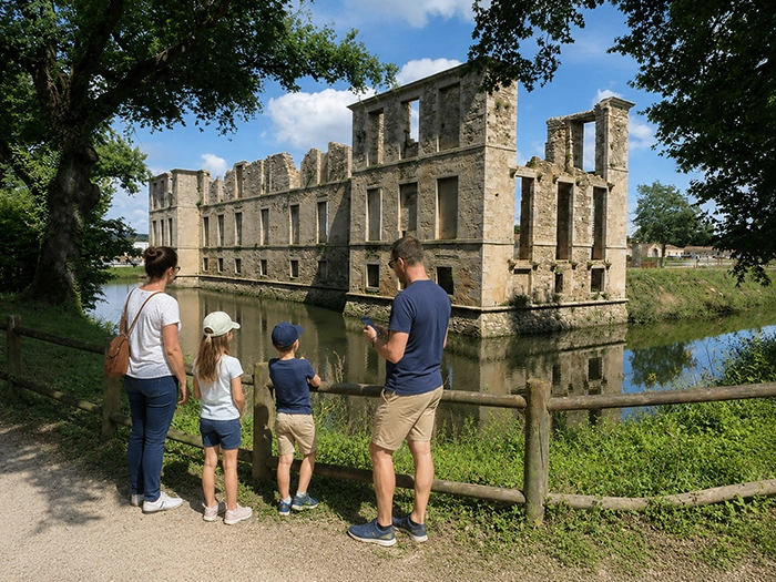 Famille avec deux enfants devant les ruines m&eacute;di&eacute;vales du ch&acirc;teau de l'&Eacute;tendu&egrave;re des Herbiers, smartphone en main, lors d'un parcours ludique en Vend&eacute;e